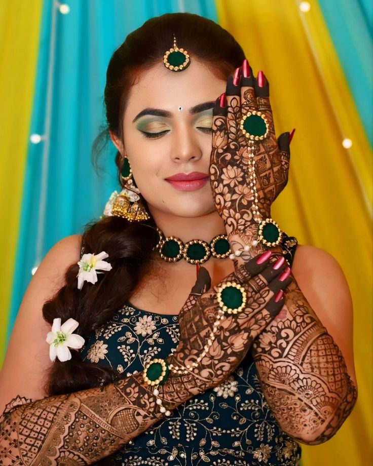 This may contain: a woman holding her hands up to her face with henna on top of it