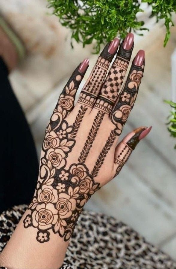 This may contain: a woman's hand with hennap on it and some plants in the background