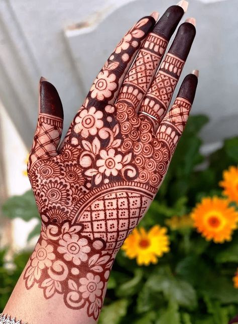 This may contain: the hand is decorated with henna on it and yellow flowers in the back ground
