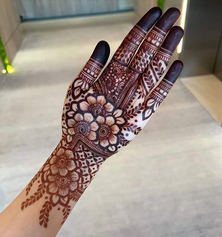 This may contain: a woman's hand is decorated with hennap and flower designs on it