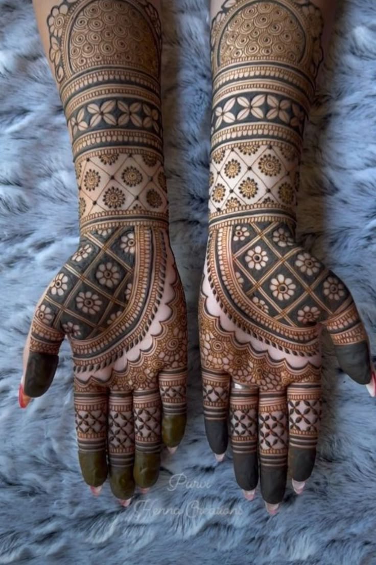 This may contain: two hands with henna tattoos on them, one is showing the intricate pattern and the other