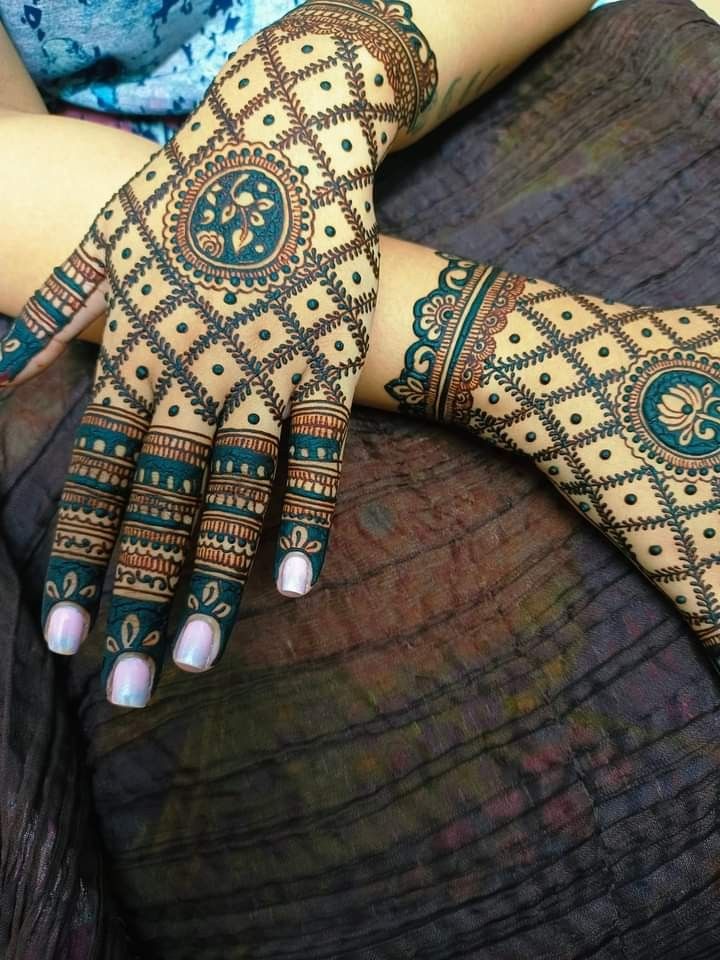 This may contain: a woman's hands with hennap on her arm and hand, both covered in intricate designs
