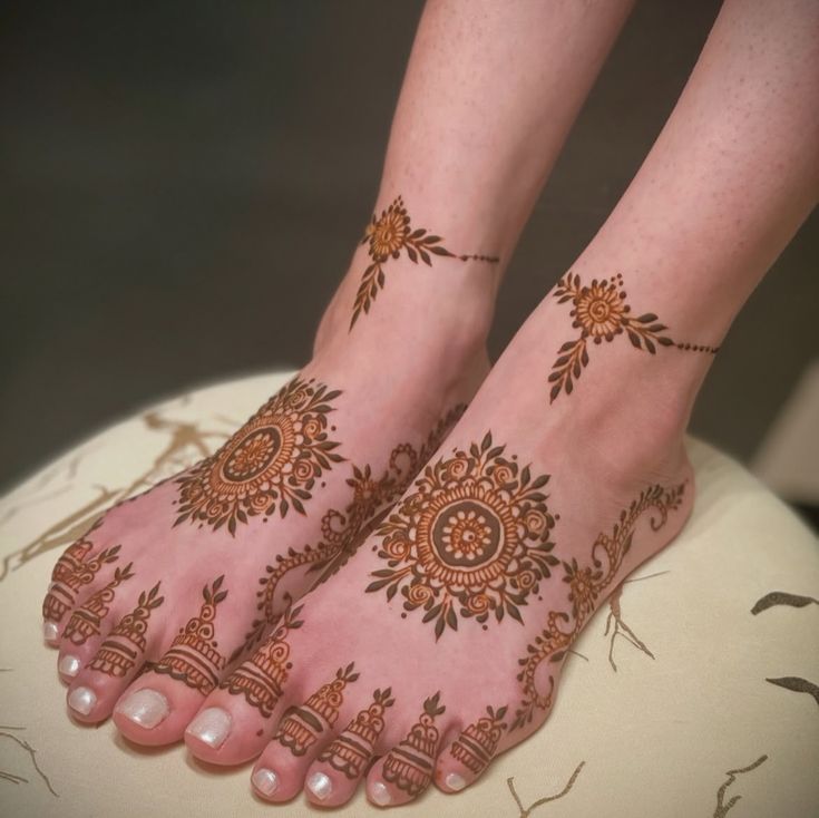 This may contain: two feet with hendi tattoos on them