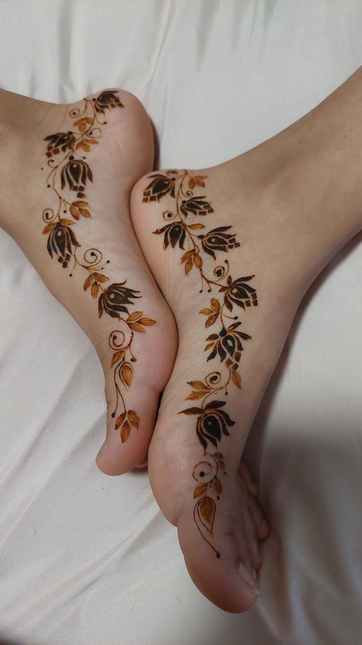 This may contain: two feet covered in hendi tattoos on top of a white bedding sheet and pillows