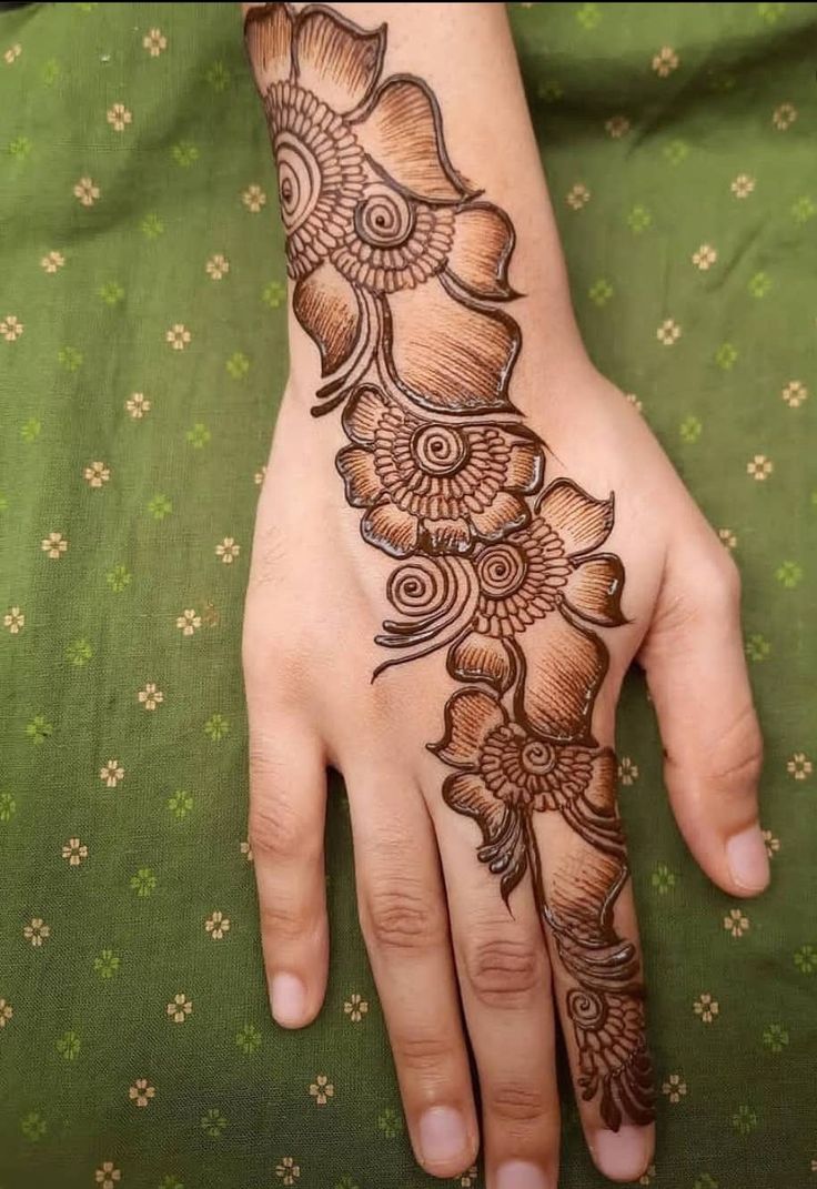 This may contain: a woman's hand with henna tattoos on it and flowers in the middle