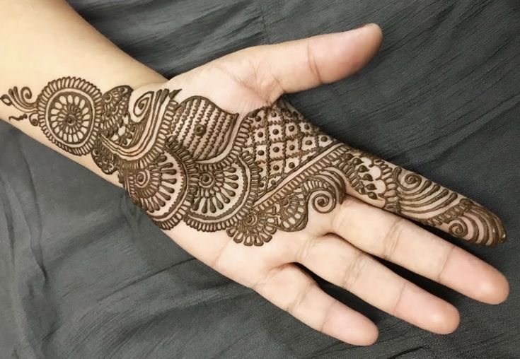 This may contain: a person's hand with henna tattoos on their arm and wrist, showing the intricate