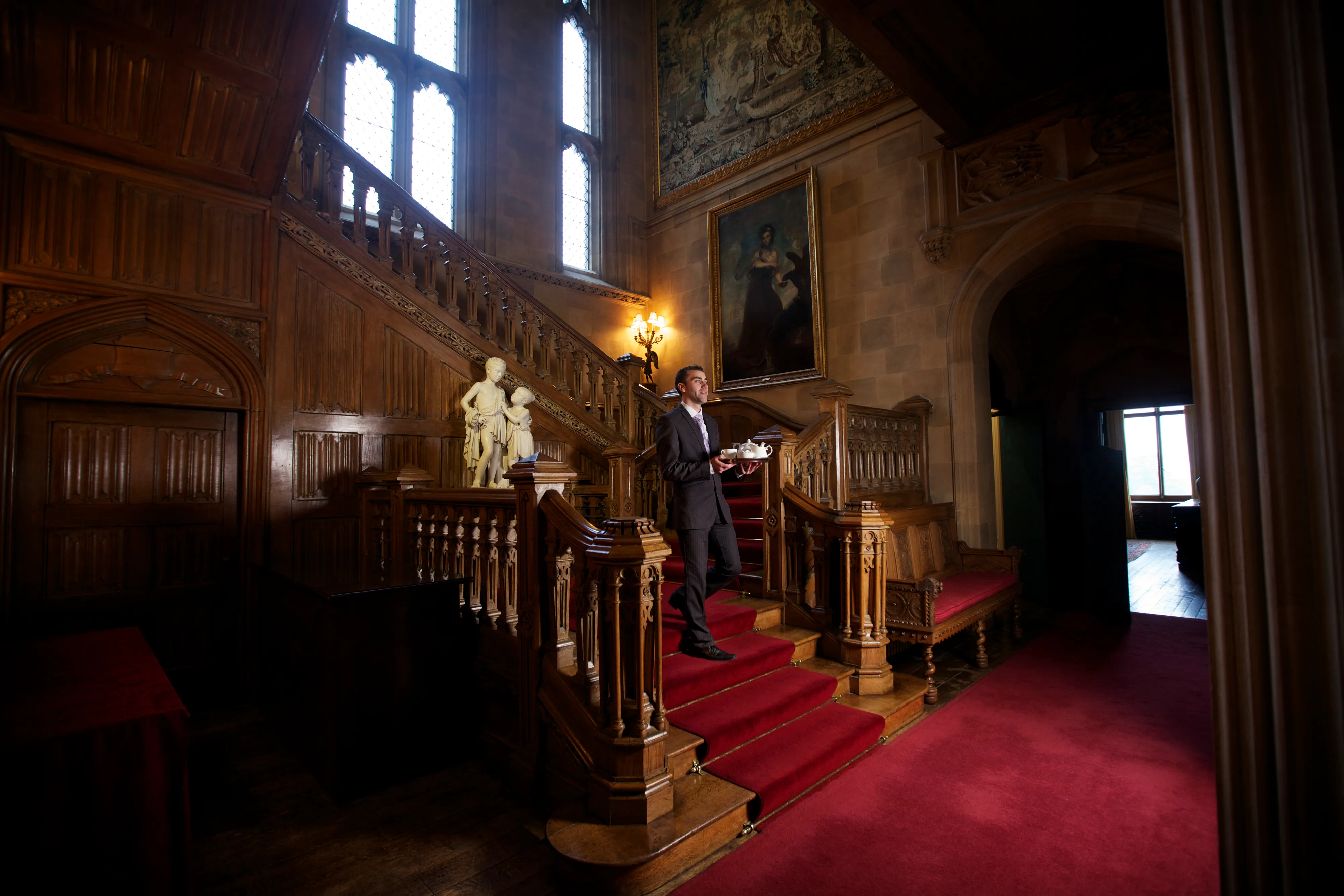 Banqueting Manager Luis Coelho serving tea on the oak staircase in Highclere Castle.