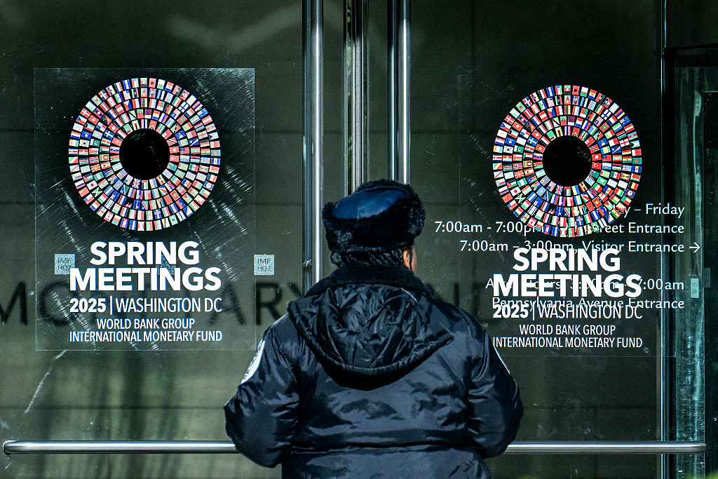 A security guard stands outside the building near signs advertising the International Monetary Fund/World Bank Spring Meetings in Washington, DC, on April 17, 2025. The World Bank and International Monetary Fund's (IMF) Spring Meetings kick off on April 14, with the Bank keen to promote its agenda to drive job creation in developing and emerging market economies. (Photo by Jim WATSON / AFP) (Photo by JIM WATSON/AFP via Getty Images)          
